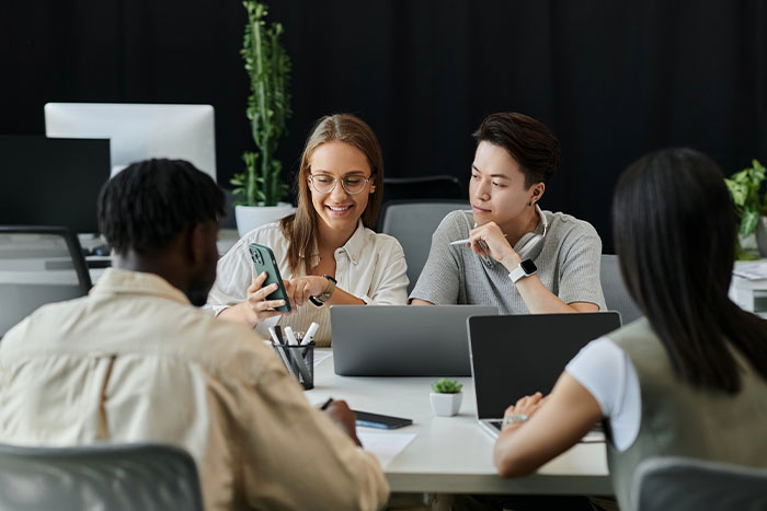 A diverse team of young professionals collaborates on a project, focused on a smartphone.