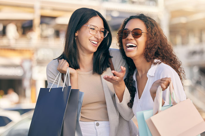 Image of two women, smiling with shopping bags.